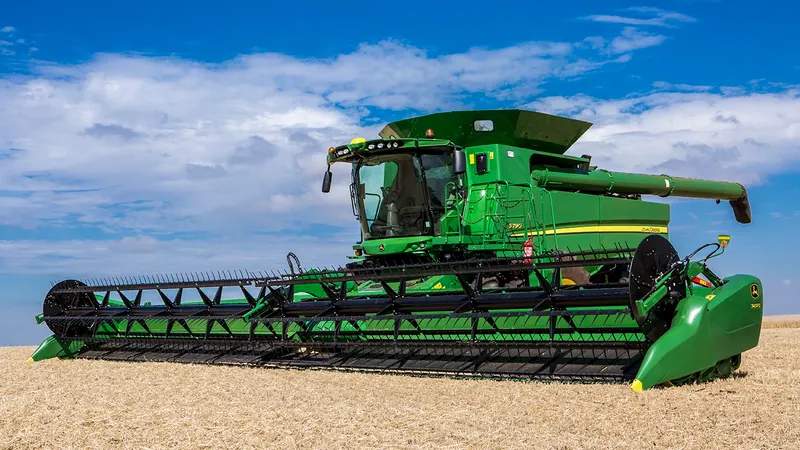 Colheitadeira John Deere S790 com plataforma na lavoura, céu azul
